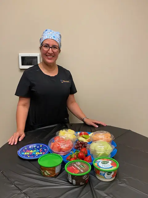 A woman standing in front of some food on the table