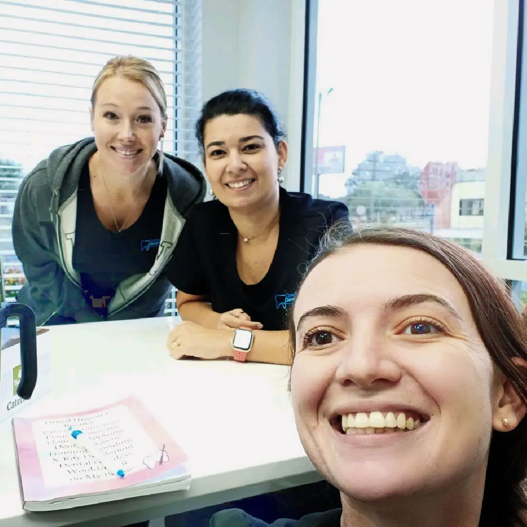 Three women sitting at a table with cake.