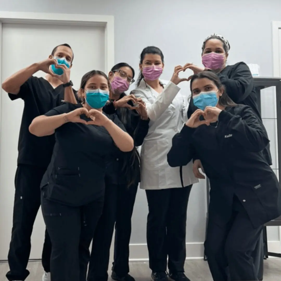 A group of people wearing masks and making heart shapes with their hands.