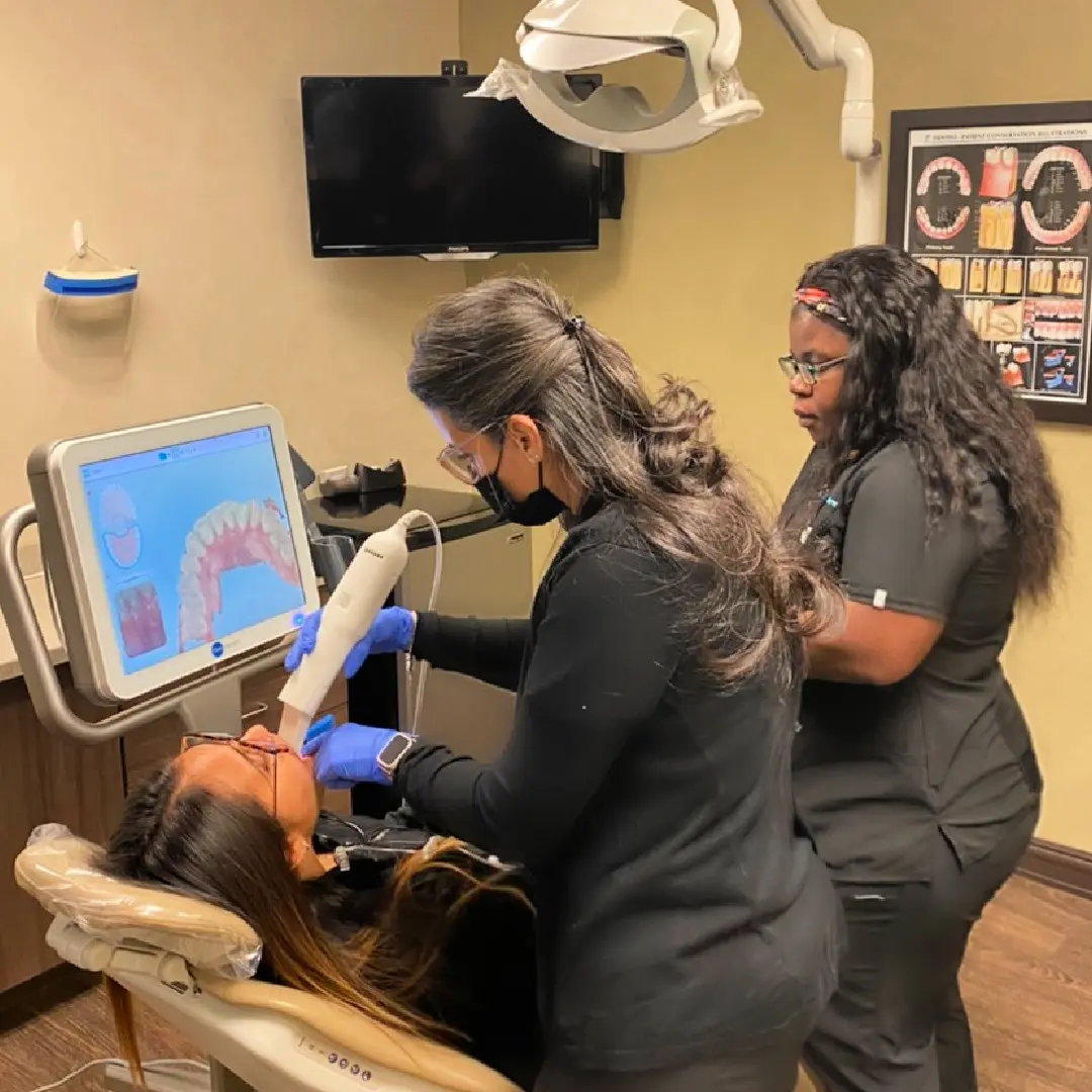 Three women are working on a patient 's teeth.