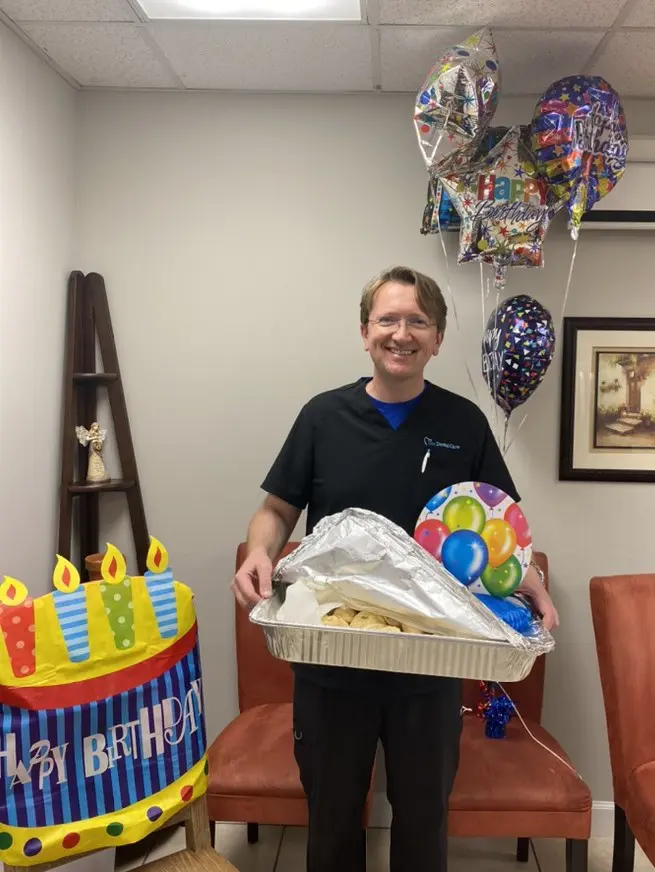 A man holding a basket of food in front of a birthday cake.