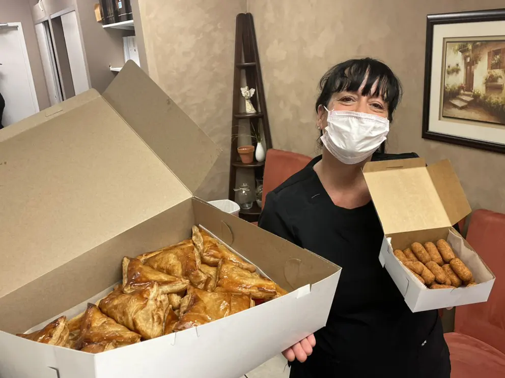 A woman holding two boxes of food in front of her face.