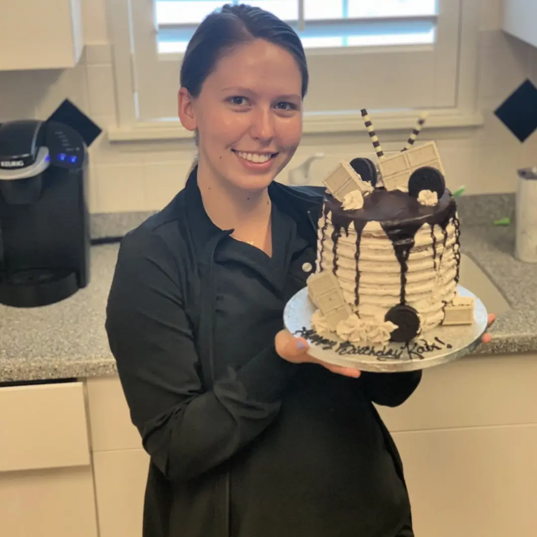 A woman holding a cake on top of a white plate.