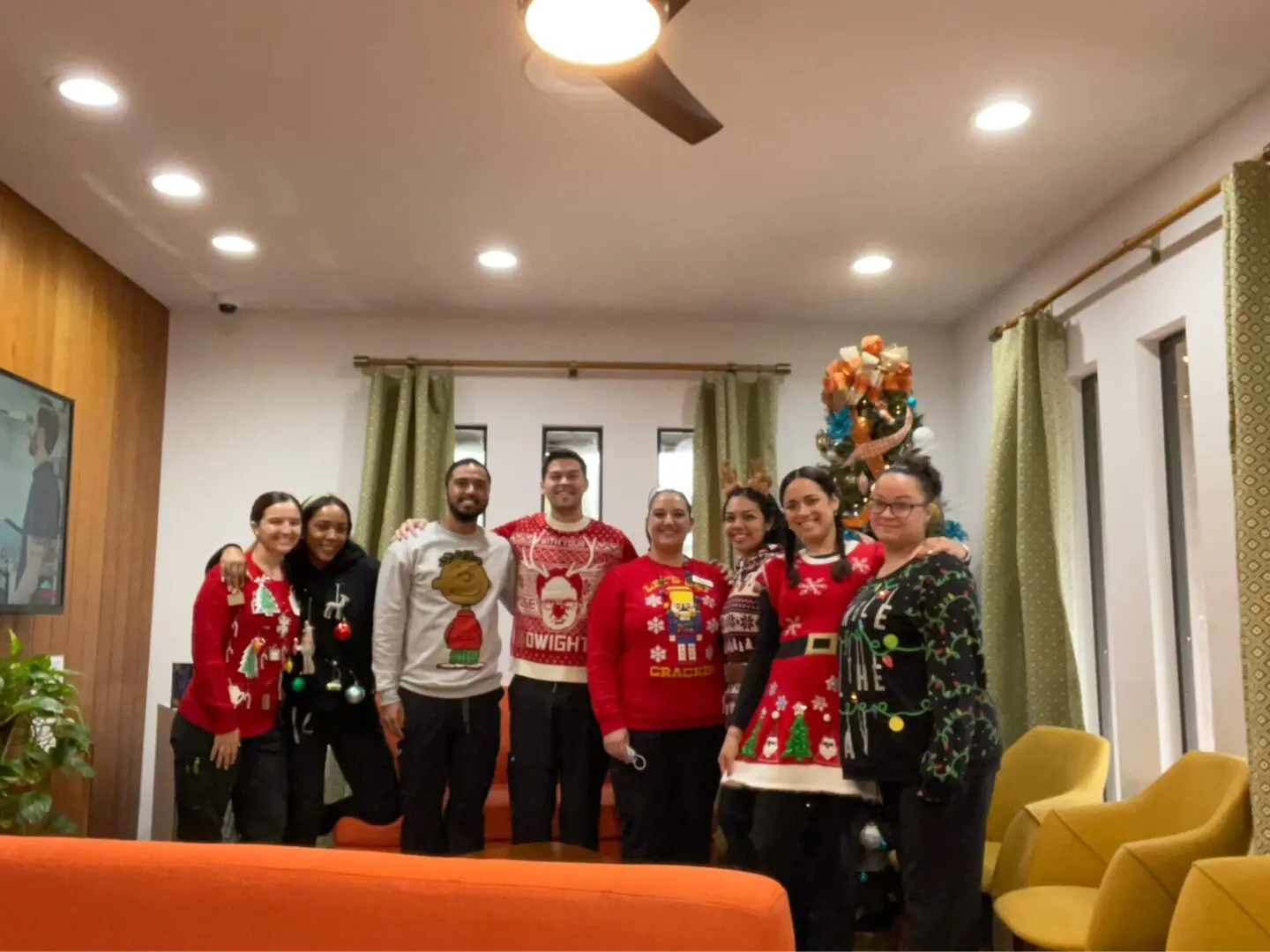 A group of people in christmas sweaters posing for the camera.