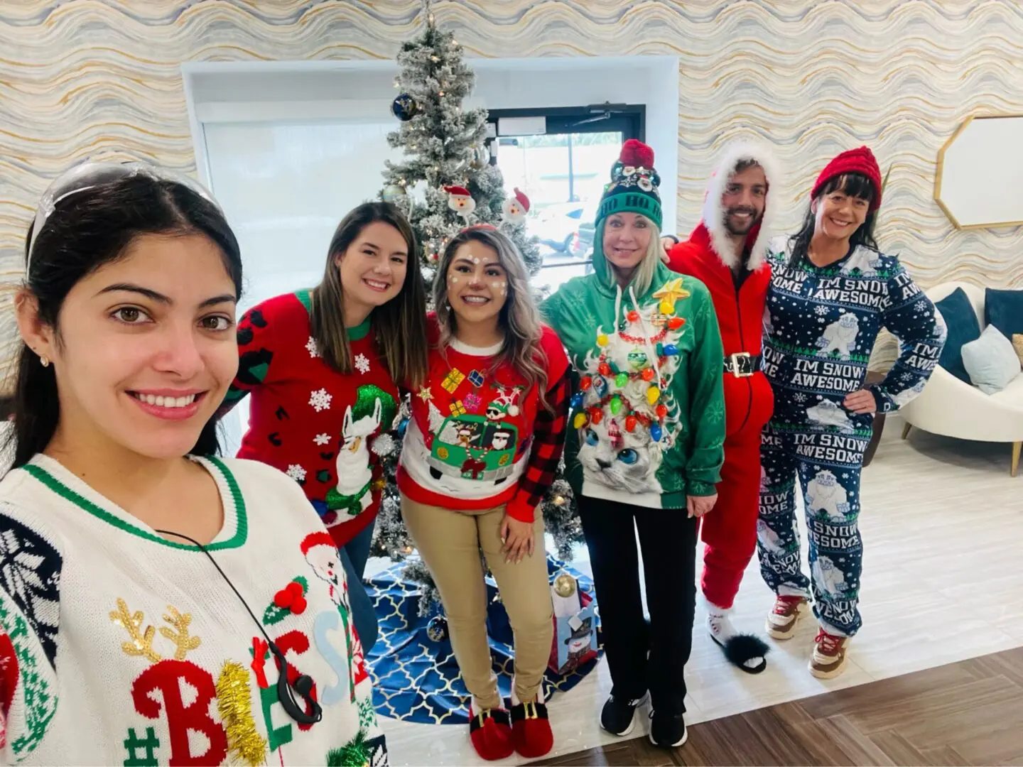 A group of people standing in front of a christmas tree.