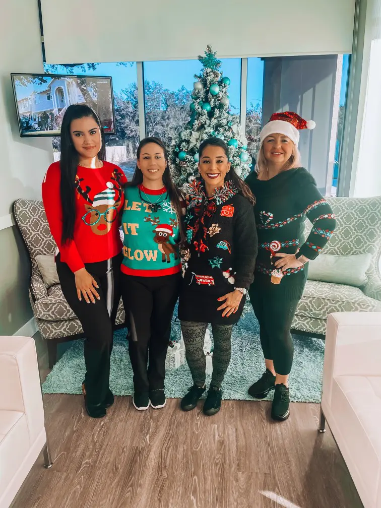 A group of women standing in front of a christmas tree.