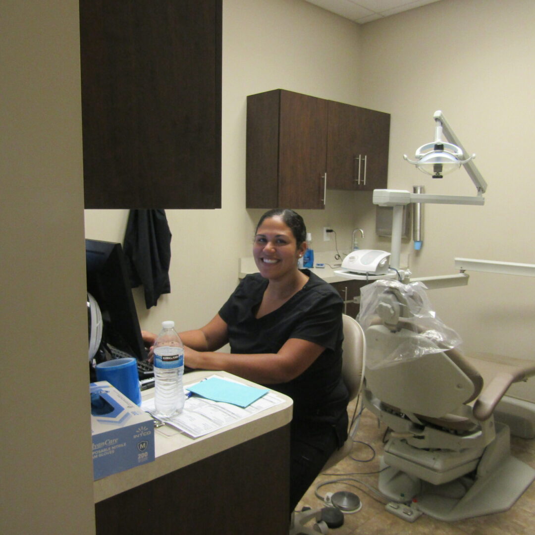 A woman sitting at the dentist 's desk in her office.