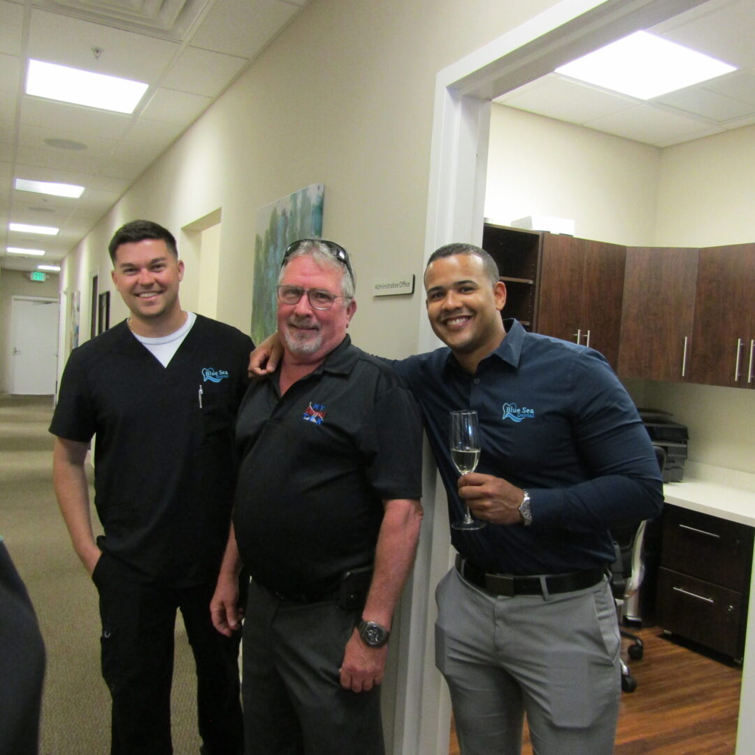 Three men standing in a room with wine.