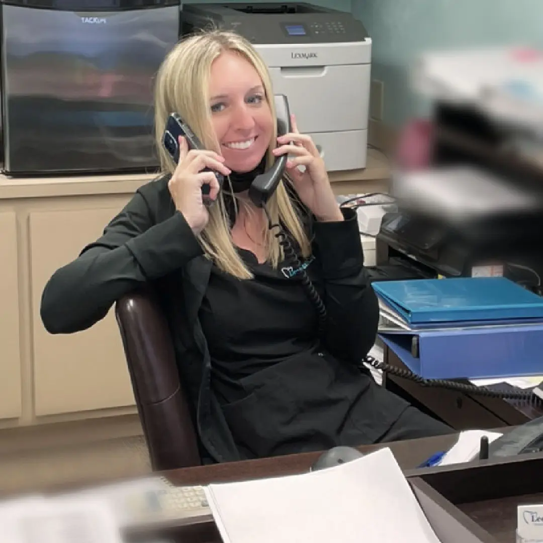 A woman sitting at her desk talking on the phone.