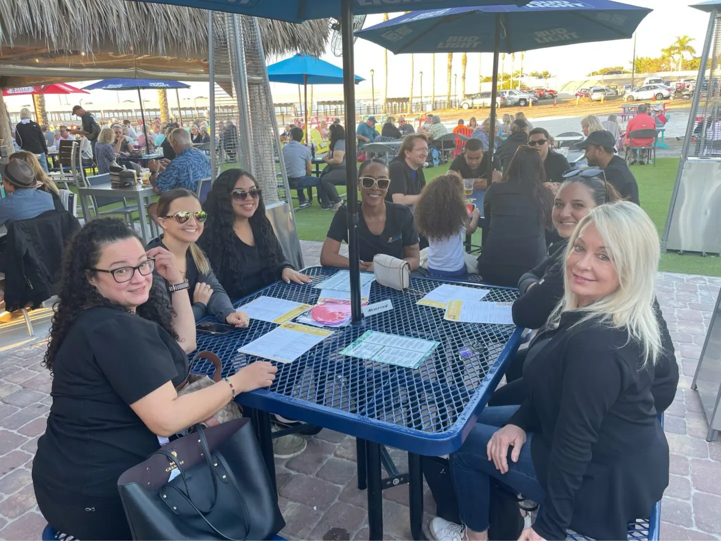 A group of people sitting at a table under umbrellas.