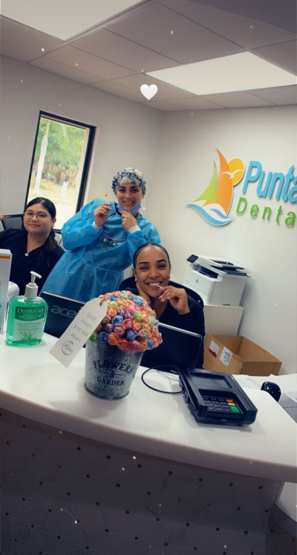 Three people sitting at a desk in front of a sign.