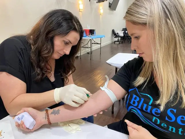 A woman getting her arm tattooed by another person.