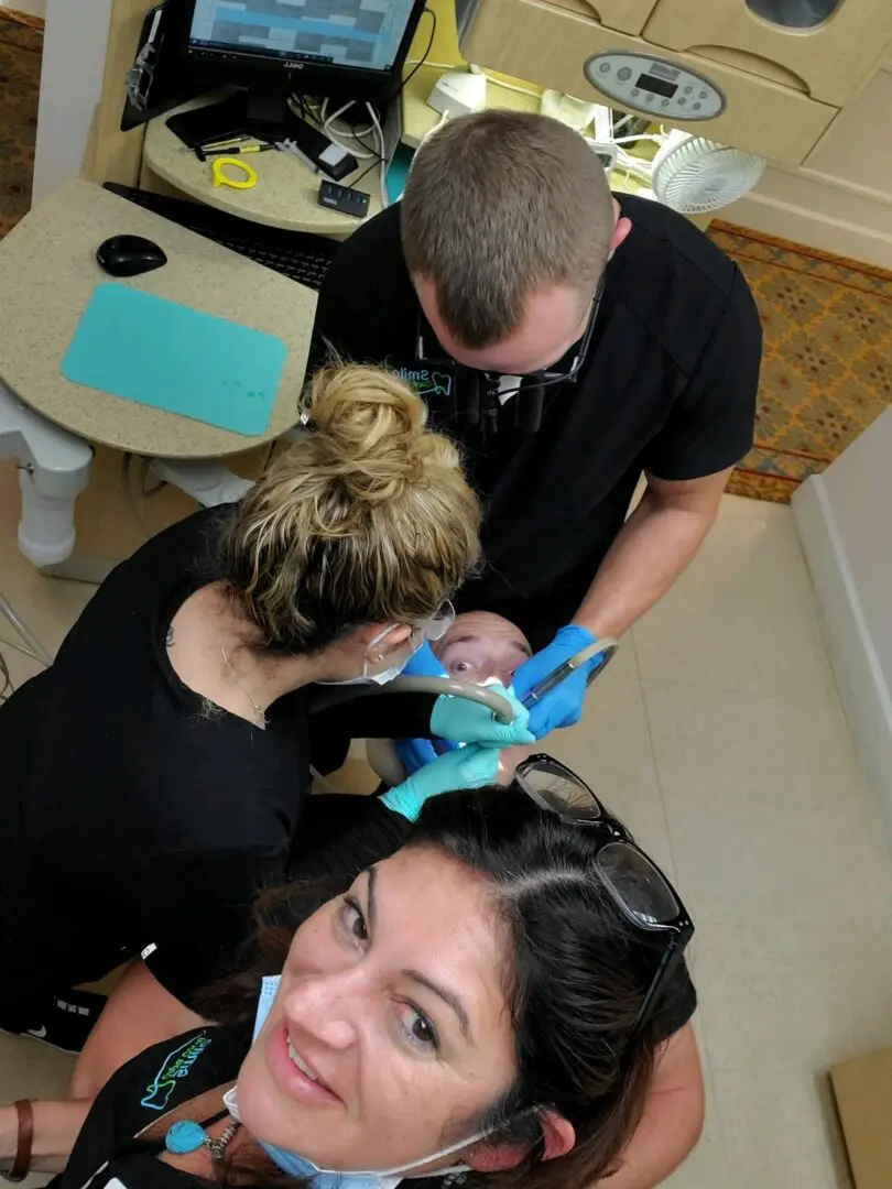 A woman getting her hair cut by two men.