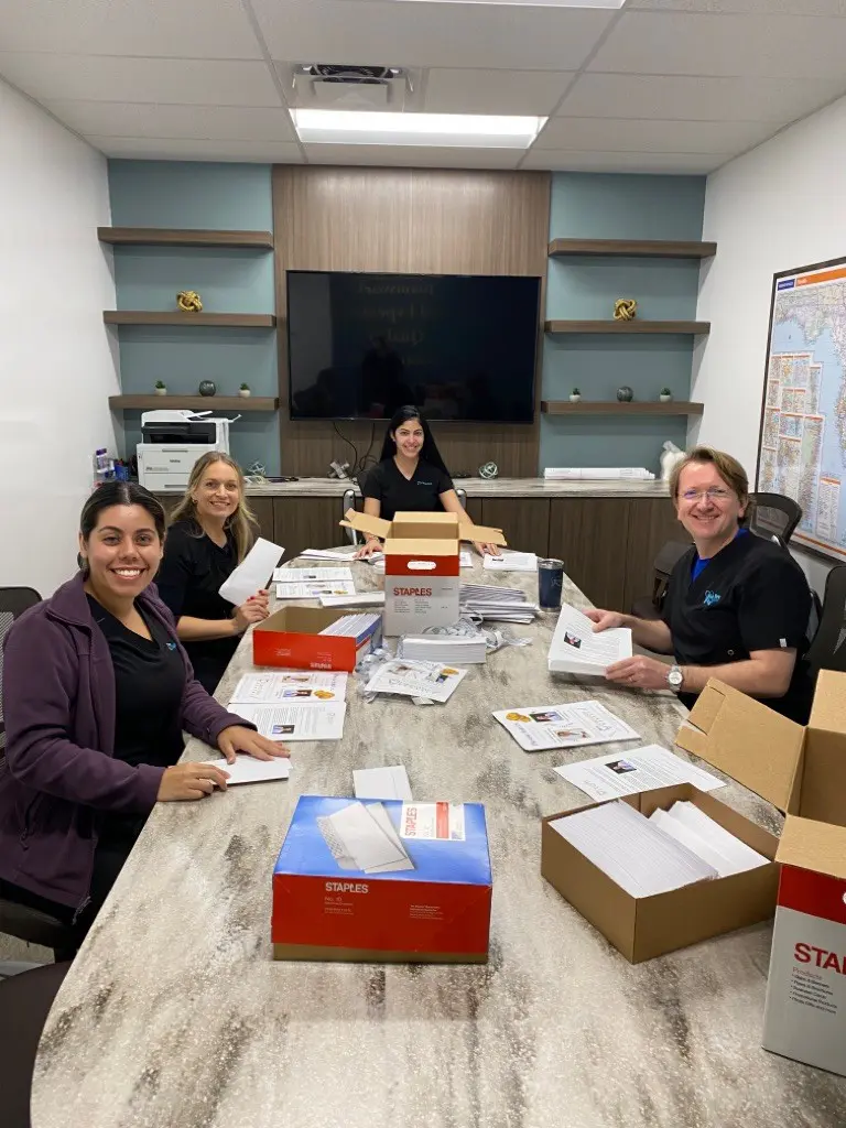 A group of people sitting around a table with boxes.