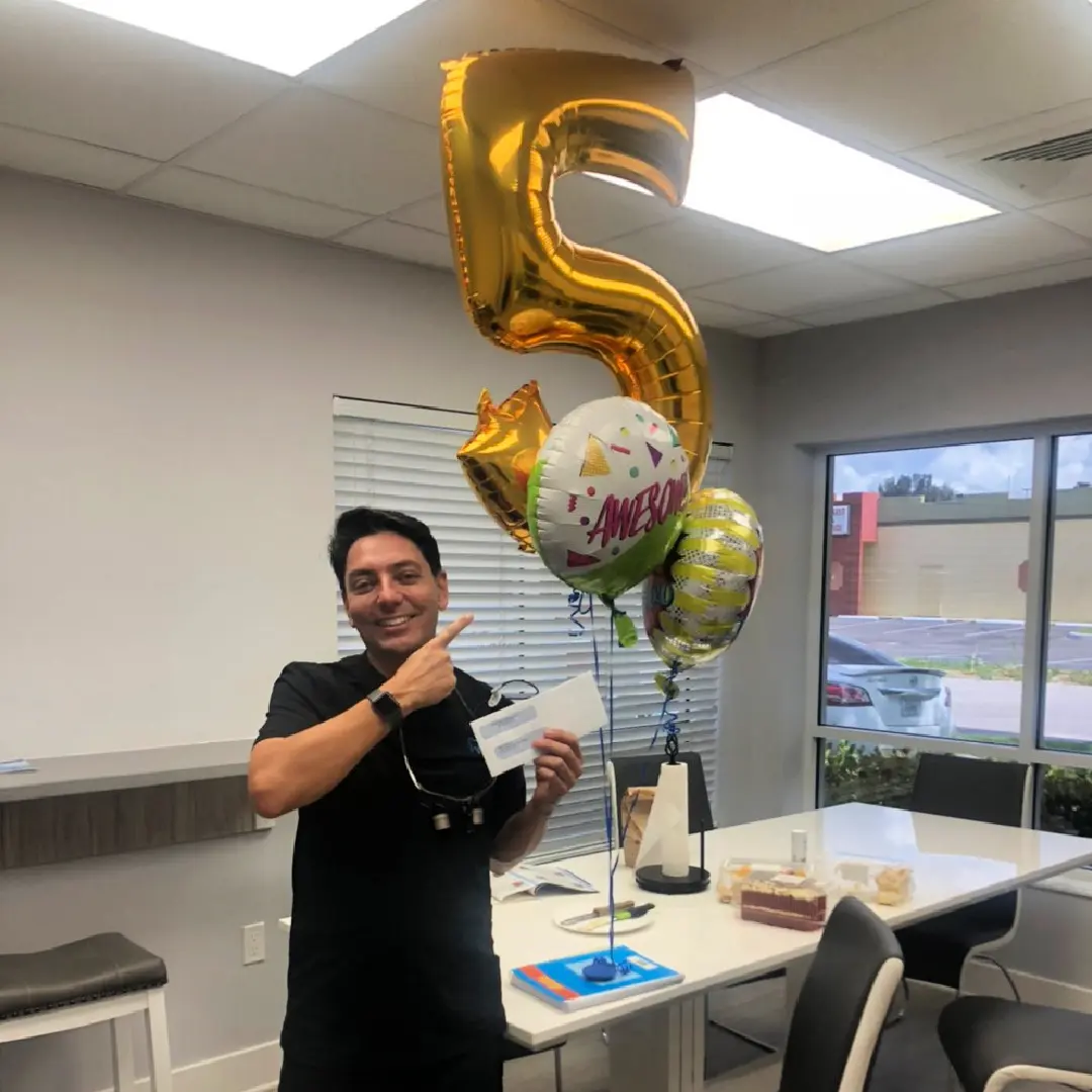 A man holding onto balloons in the shape of number five.