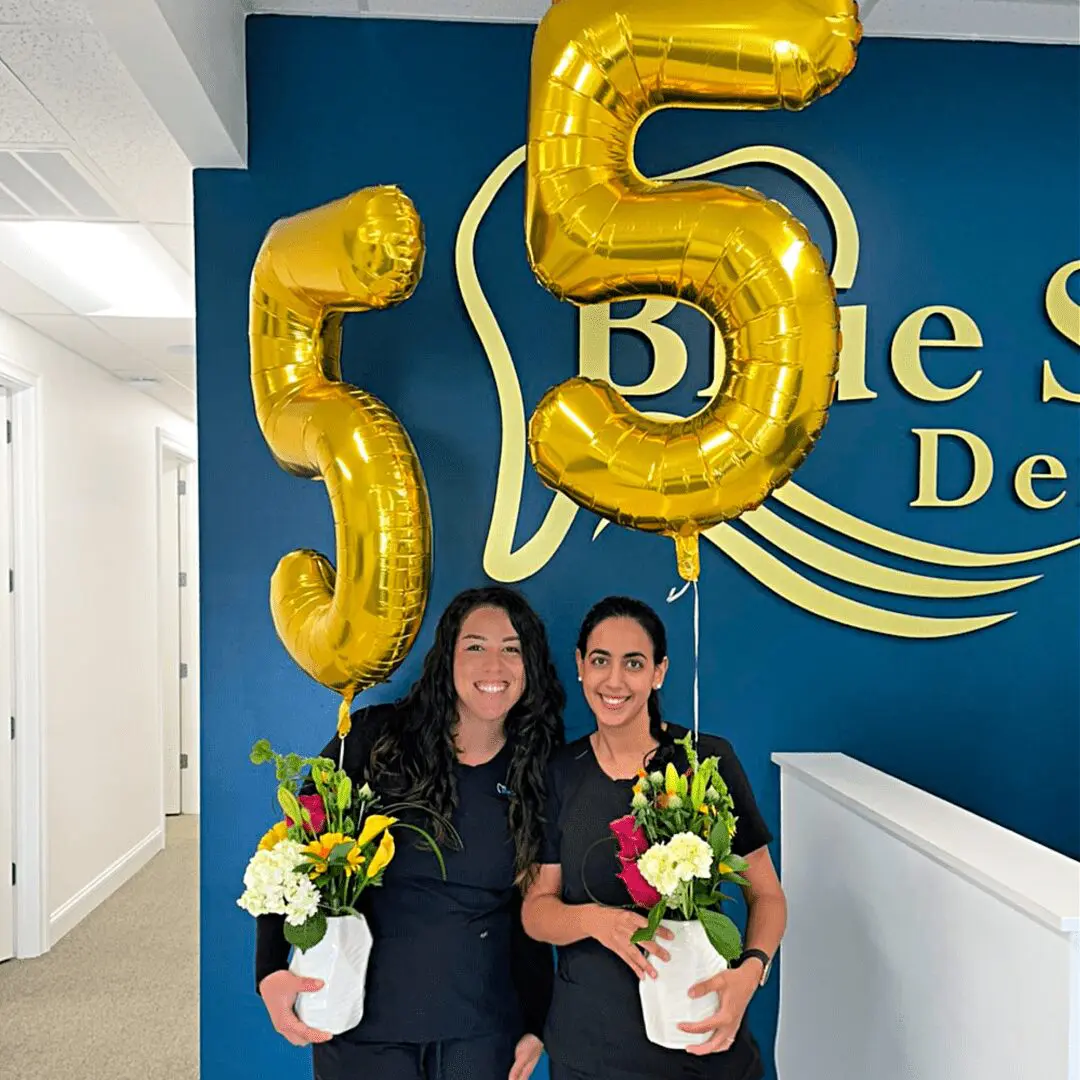 Two women holding balloons that say " 5 5 ".