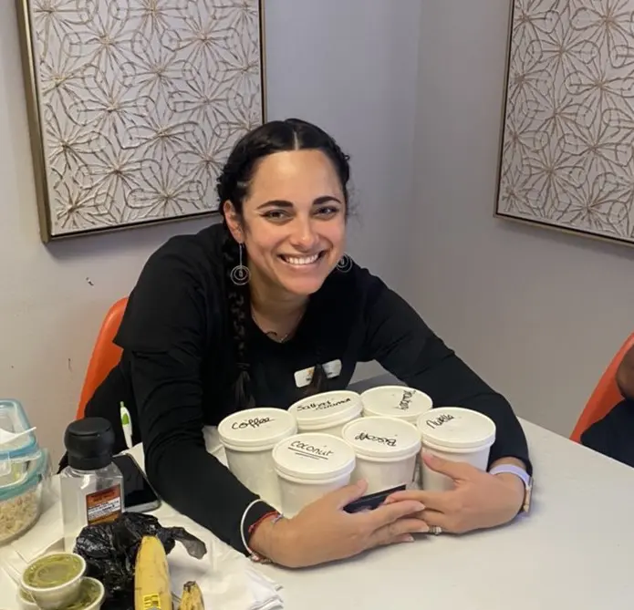 A woman sitting at the table with many cups of coffee.