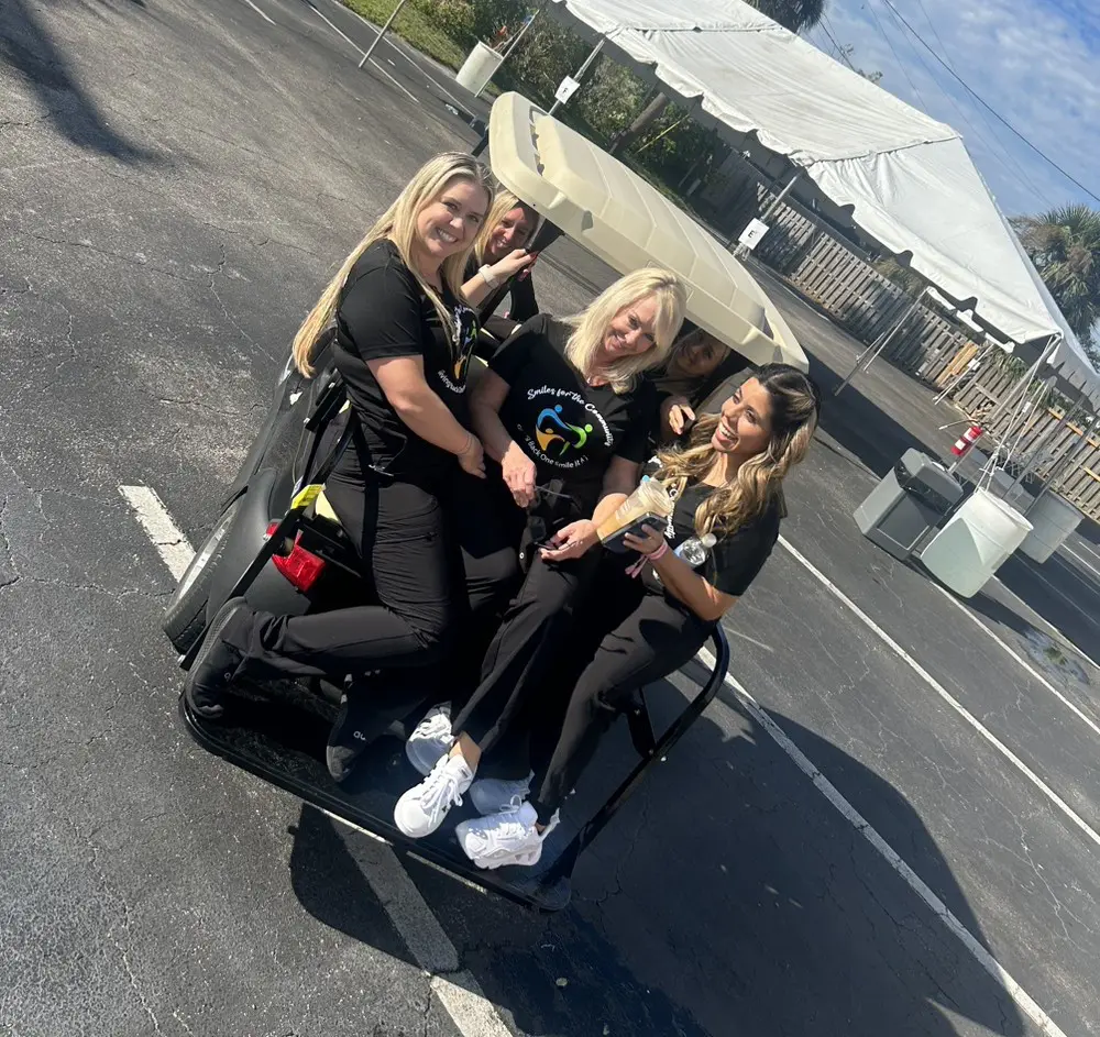 Three women sitting on a bench in the middle of an open road.