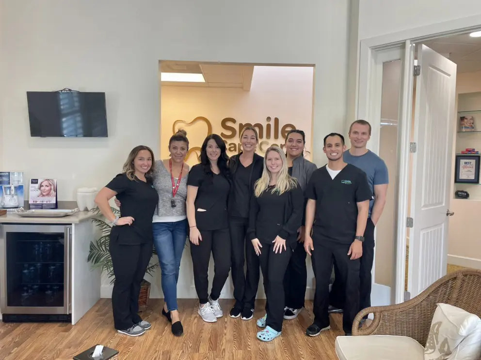 A group of people standing in front of a smile center sign.