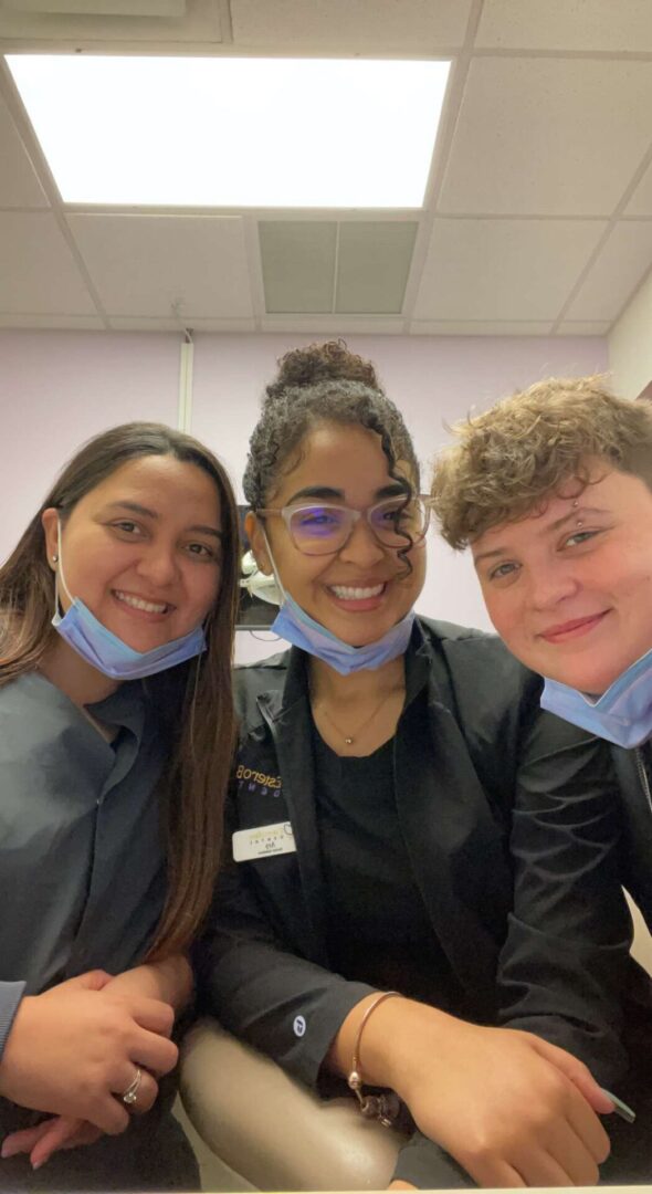 Three people wearing masks pose for a picture.