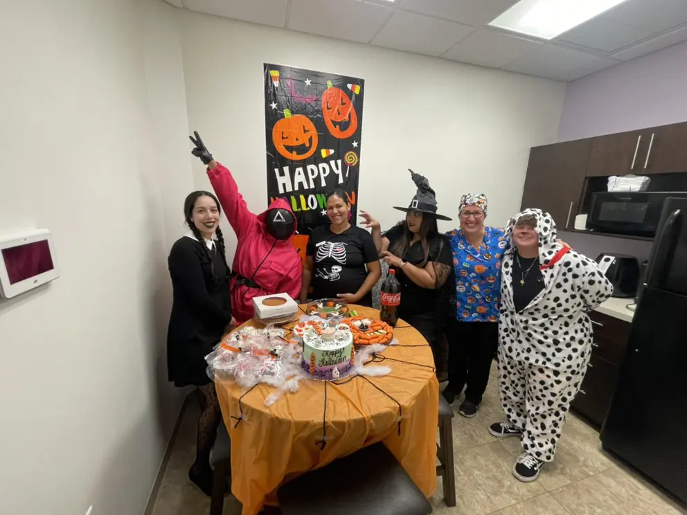 A group of people standing around a table with cake.