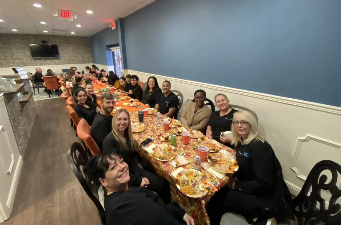 A group of people sitting at a long table with food.