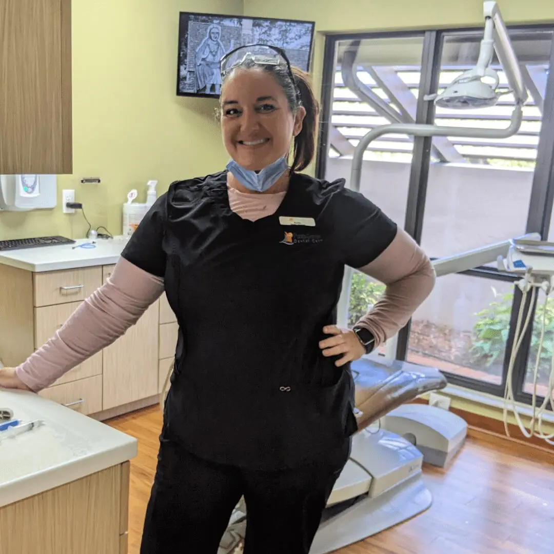 A woman standing in front of a dentist 's office.