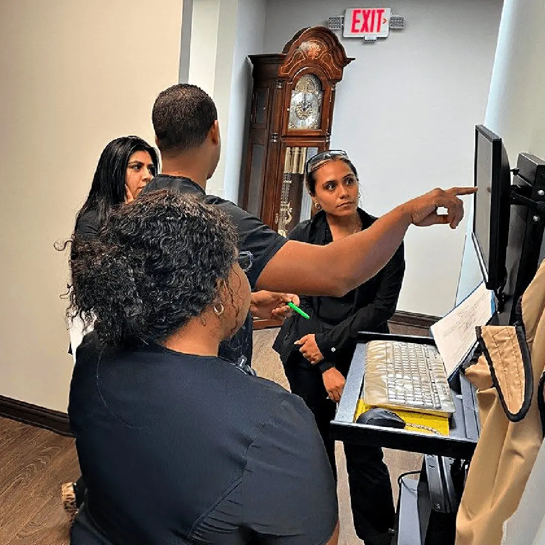 A group of people standing around a computer.