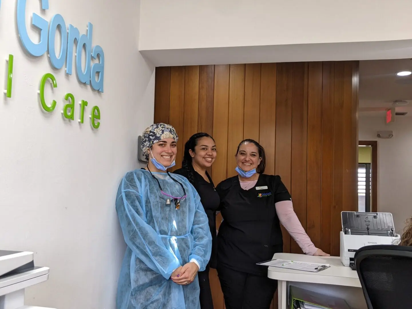 Three women standing in front of a sign.