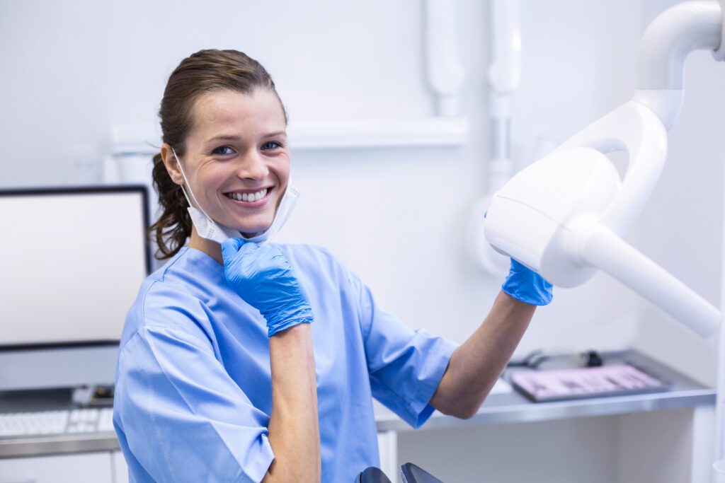 A female dentist smiling and wearing a mask