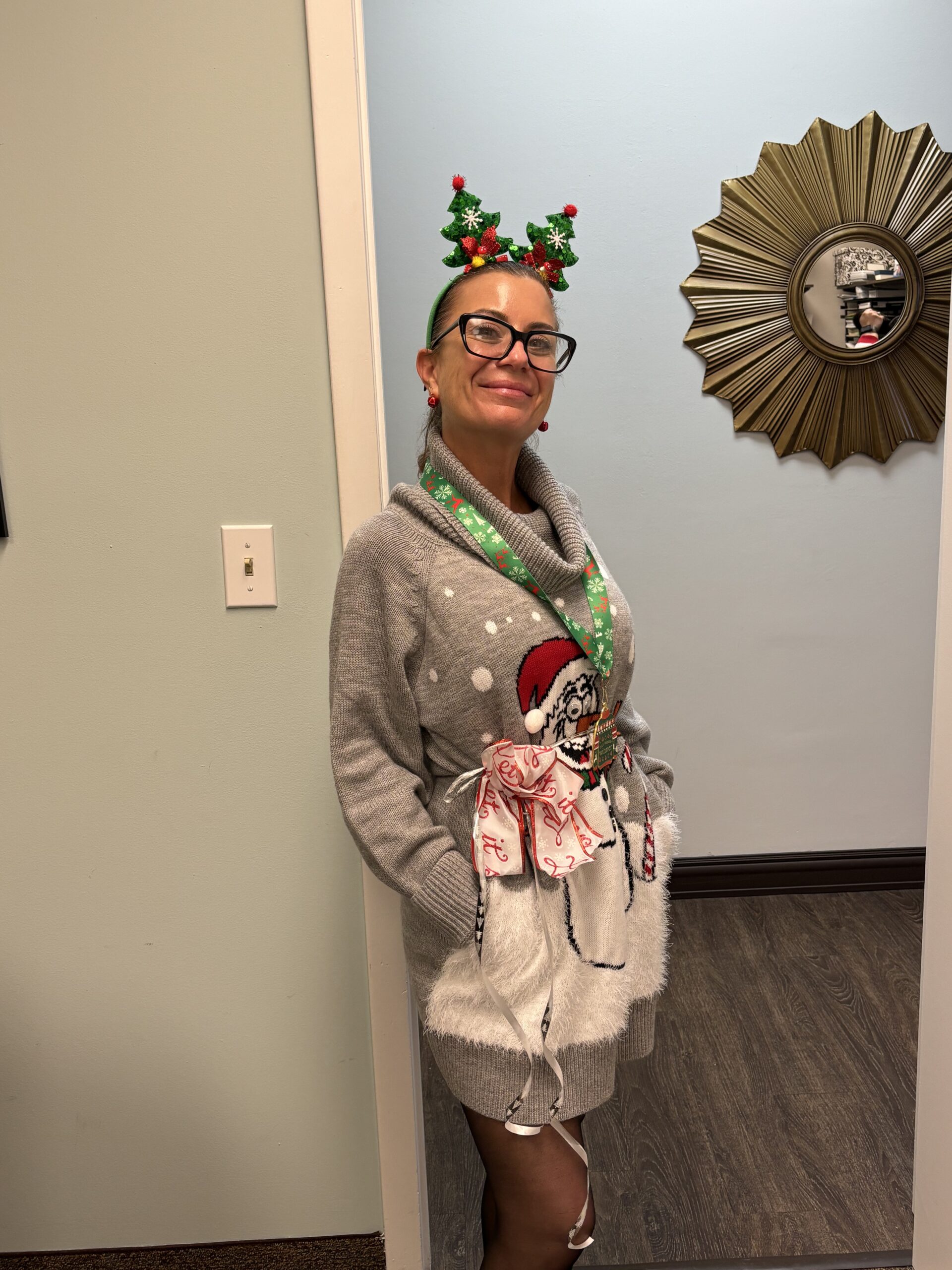 A woman standing in front of a mirror wearing christmas decorations.