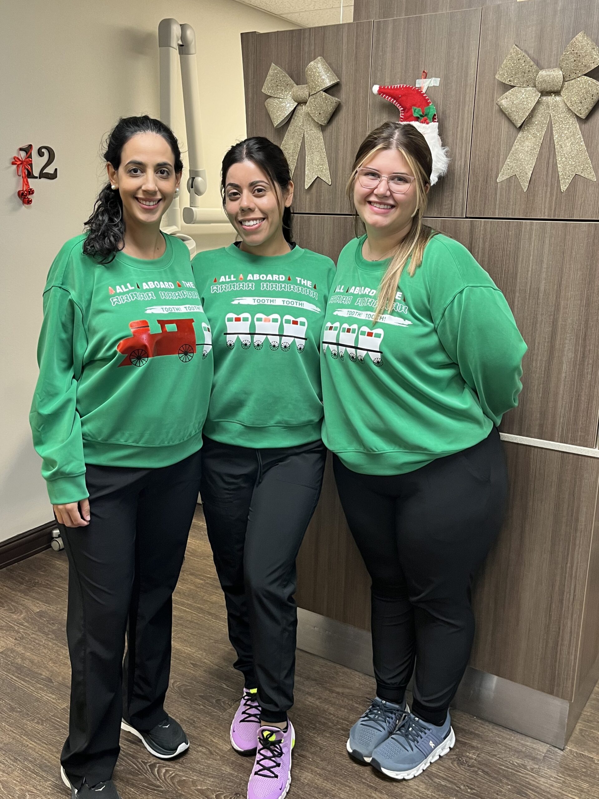 Three women wearing green shirts and black pants.