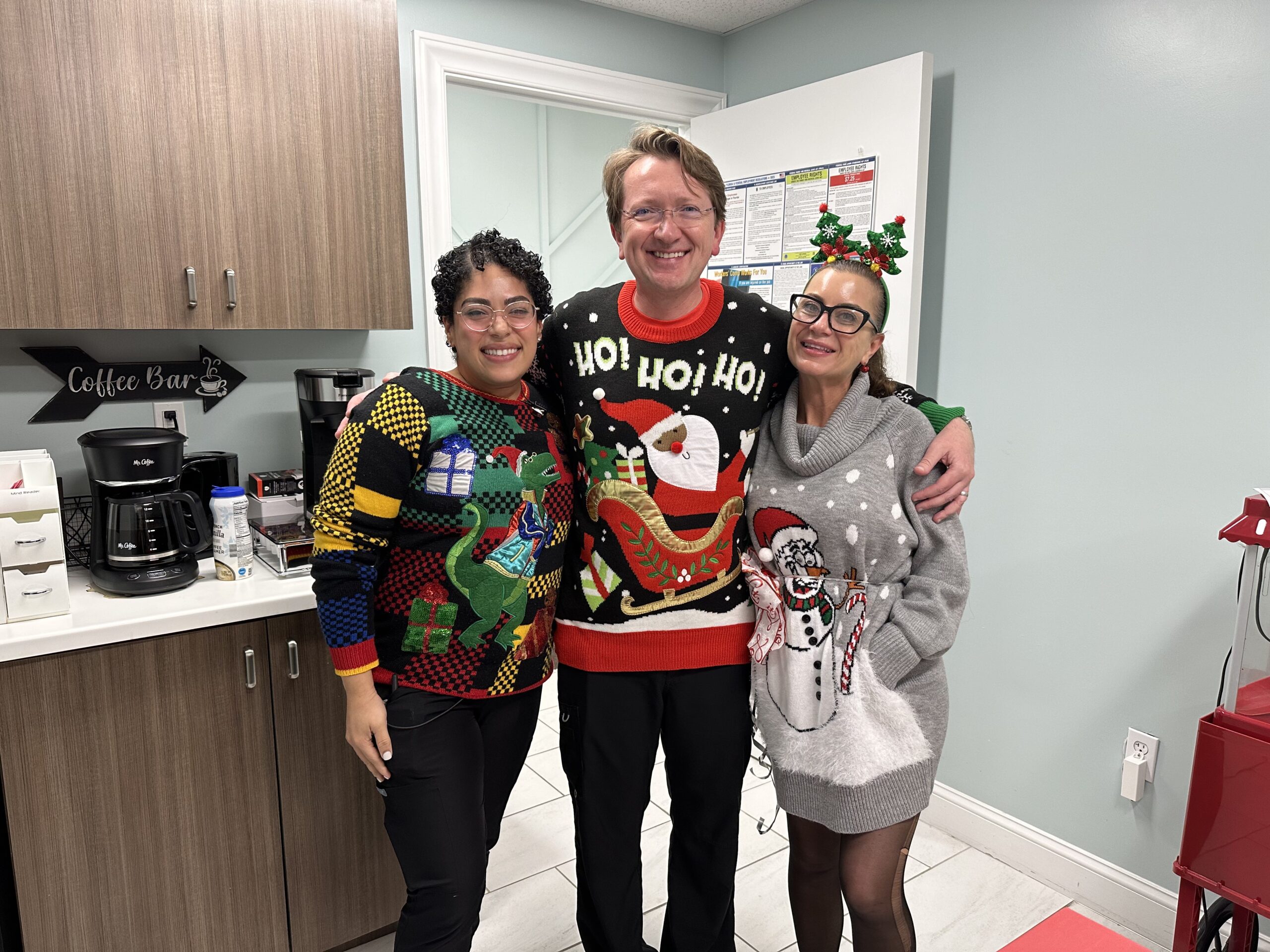 Three people in christmas sweaters posing for a picture.