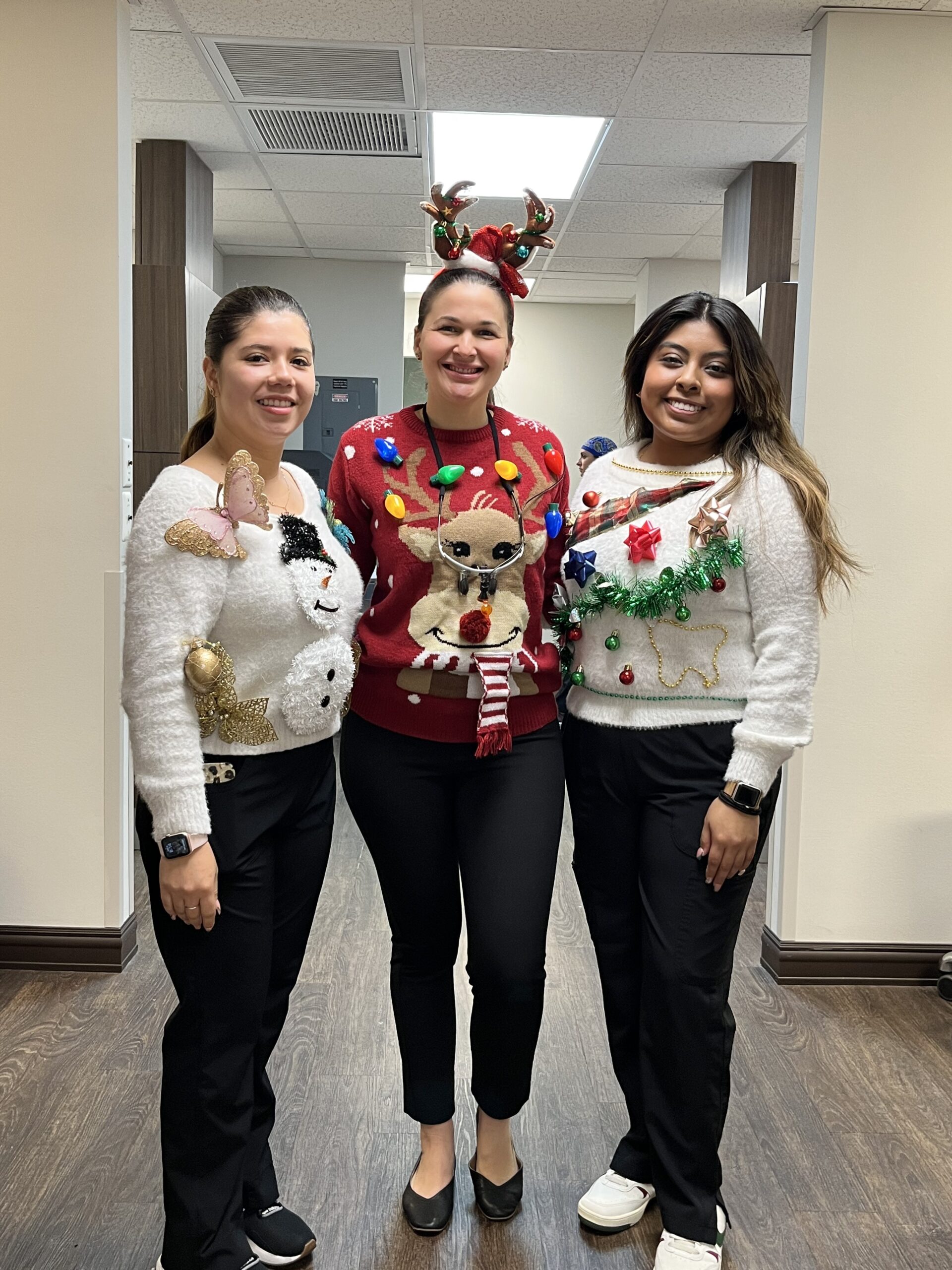 Three women in christmas sweaters posing for a picture.