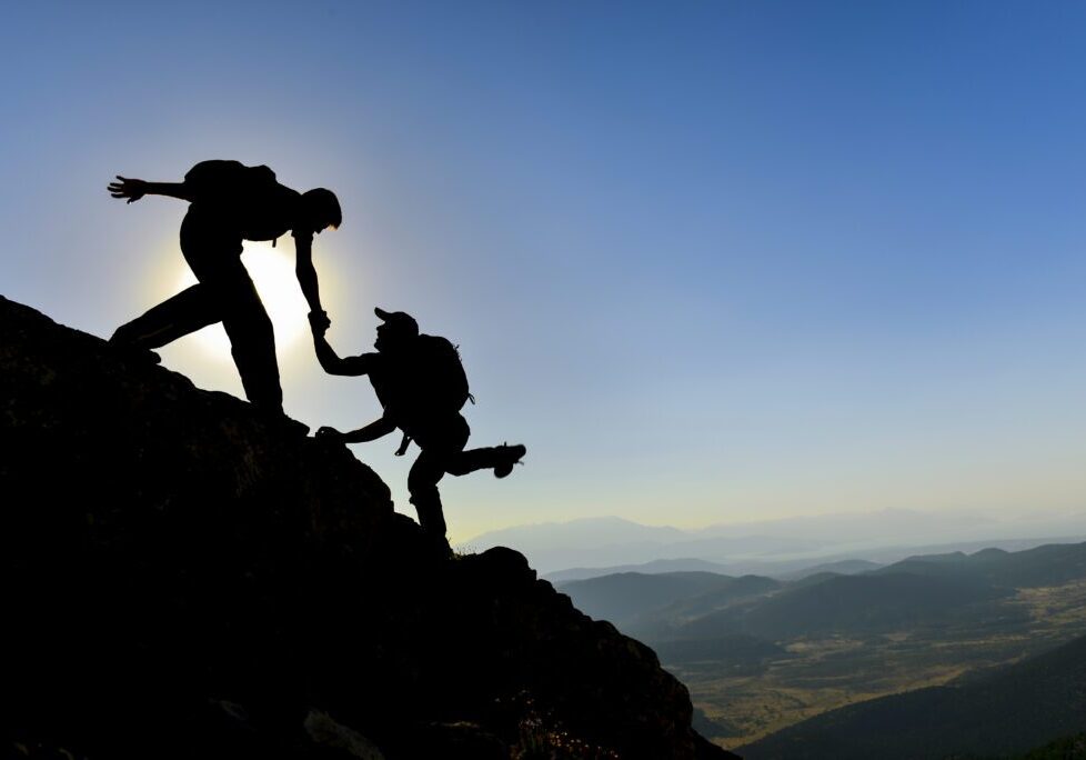 Two people climbing up a mountain on top of it