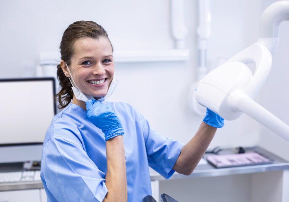 A woman in blue scrubs holding up a white object.