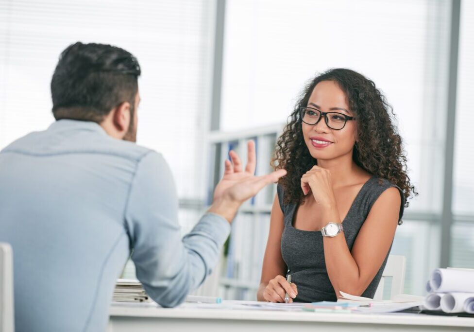 A woman sitting at a table talking to another person.